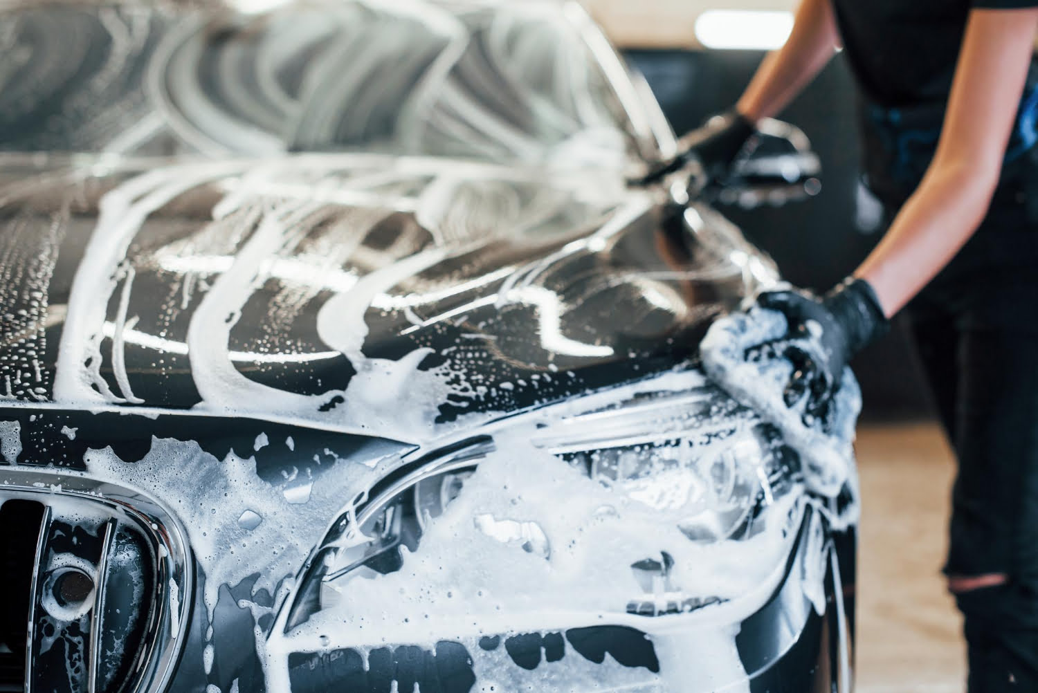 wipes-vehicle-that-is-white-soap-modern-black-automobile-get-cleaned-by-woman-inside-car-wash-station